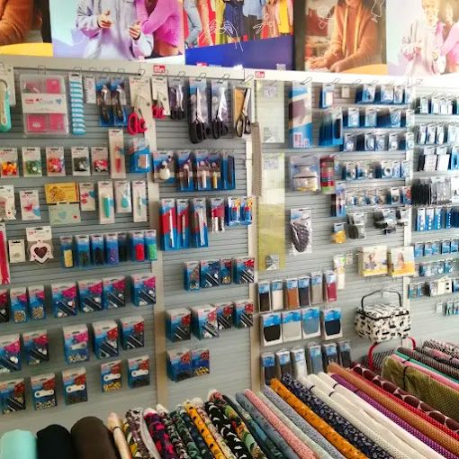 Bunt sortierte Nähmaterialien wie Garne, Knöpfe und Bänder in einem Geschäft angeordnet.