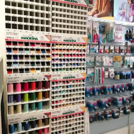 Regal mit Nähgarn in verschiedenen Farben und Zubehör für Näharbeiten.