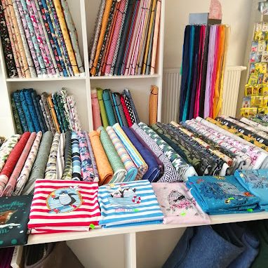 Eine Sammlung von bunten Stoffen in verschiedenen Mustern und Farben auf Regalen.