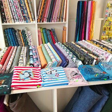 Bunte Stoffe in verschiedenen Mustern und Farben auf einem Tisch angeordnet.